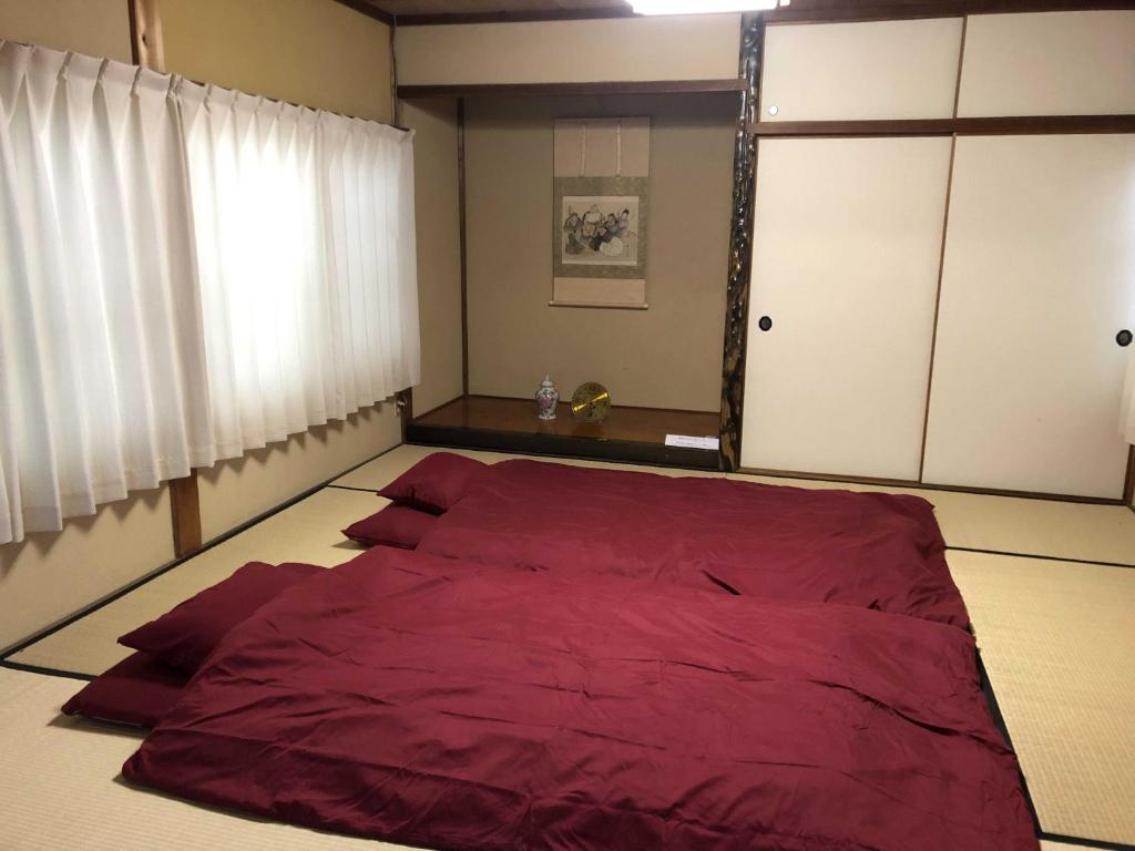 Cette chambre comprend un grand lit rouge et une fenêtre. dans l'établissement GINGAYA, à Iwataki