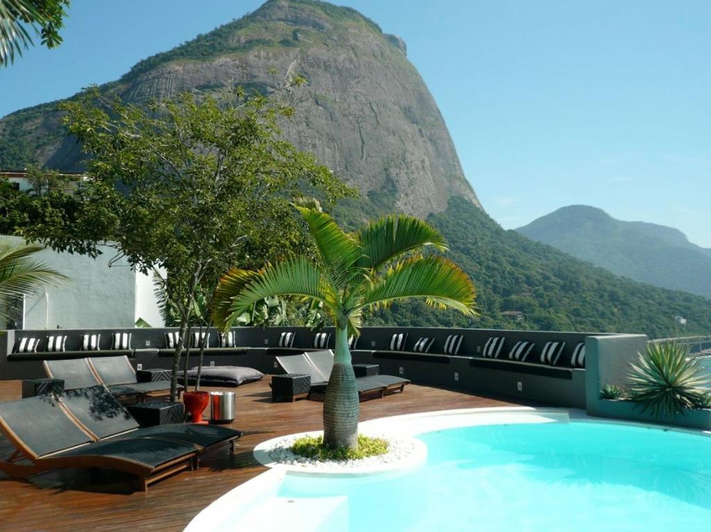 a resort with a pool and a mountain in the background at La Suite by Dussol in Rio de Janeiro