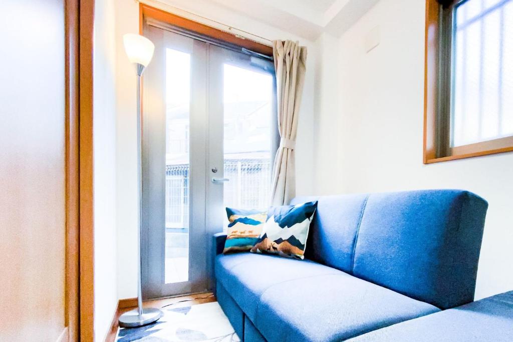 un canapé bleu dans une pièce avec une fenêtre dans l'établissement Yahiro 4-chome House 1F, à Tokyo