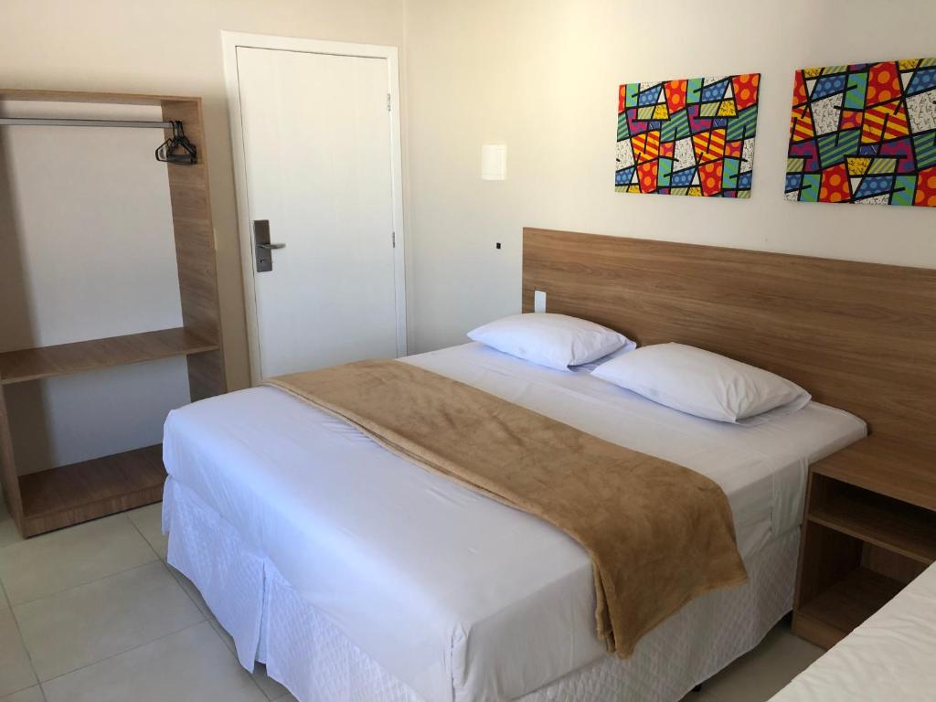 Schlafzimmer mit einem großen Bett mit einem Kopfteil aus Holz in der Unterkunft Hotel QualitySul in Teixeira de Freitas
