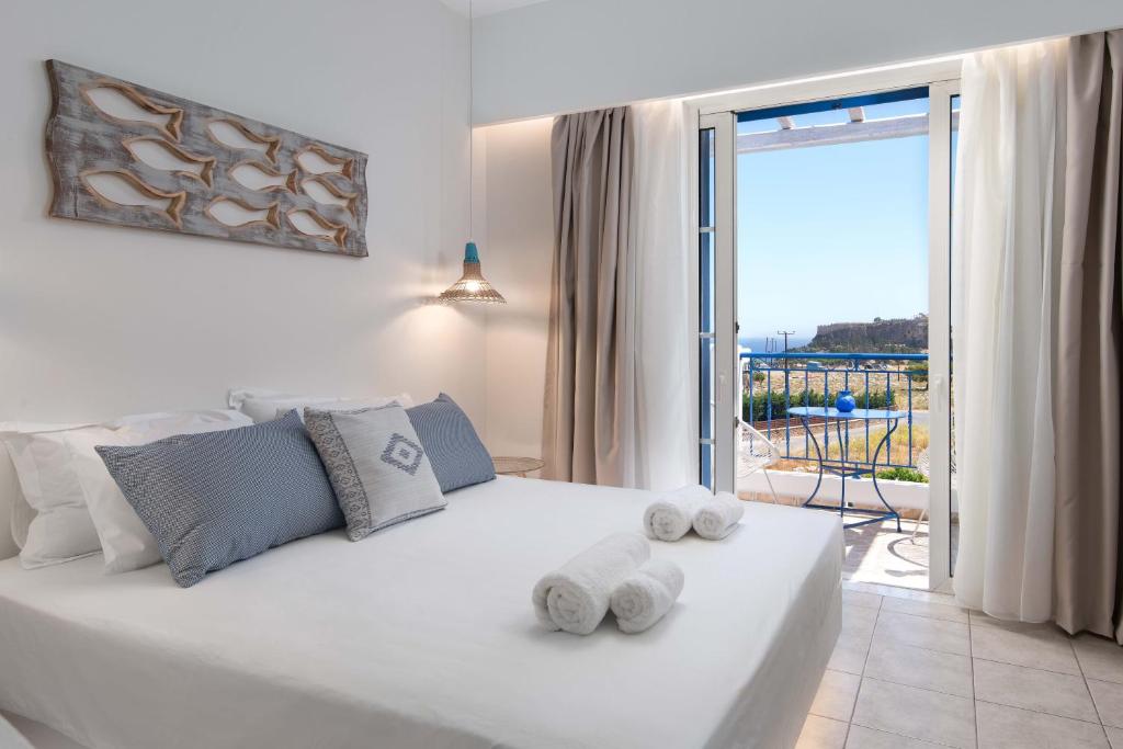 a bedroom with a white bed with towels on it at 'Lindian Myth' Sea View Studios in Líndos