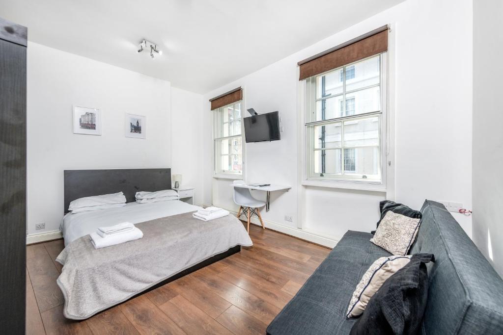 a bedroom with two beds and a couch at Soho Central Apartments in London
