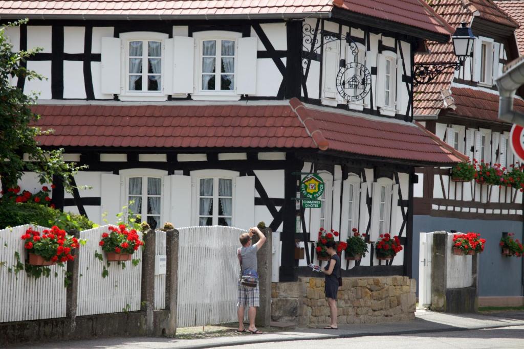 two people standing in front of a building at Gîtes et chambres d'hôtes Maison Ungerer in Hunspach