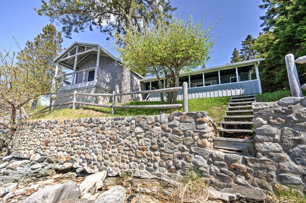 una casa en una colina con una pared de piedra en Bayfront Hancock Cottage with Beach Access and Views! en Hancock