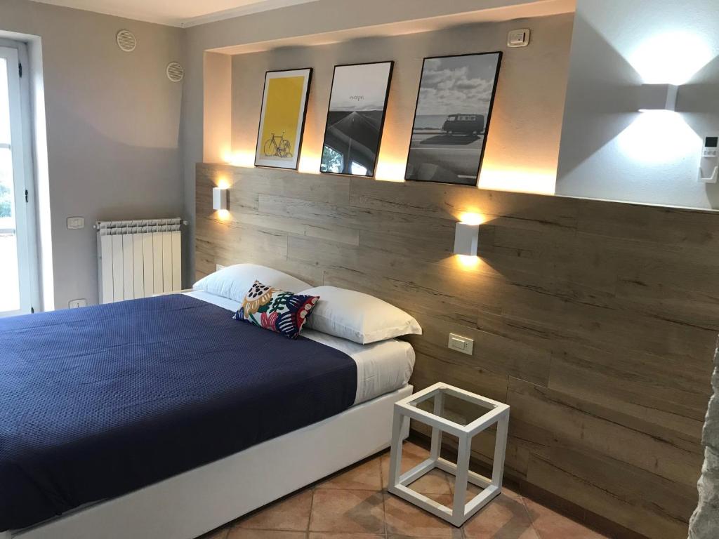 1 dormitorio con cama azul y pared de madera en Le Coste Casa Vacanze, en Scarlino