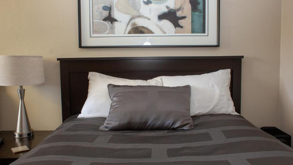 a bed with a pillow and a picture on the wall at Mark III, INN & Suites in Scottdale