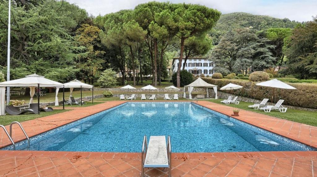 een groot zwembad met stoelen en parasols bij Relais Villa Montecatini in Camaiore