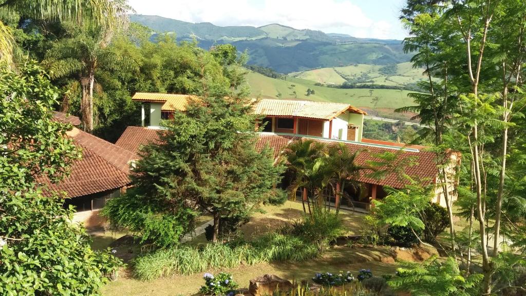 a house in the jungle with mountains in the background at Pousada Campestre Sítio da Lua in Camanducaia