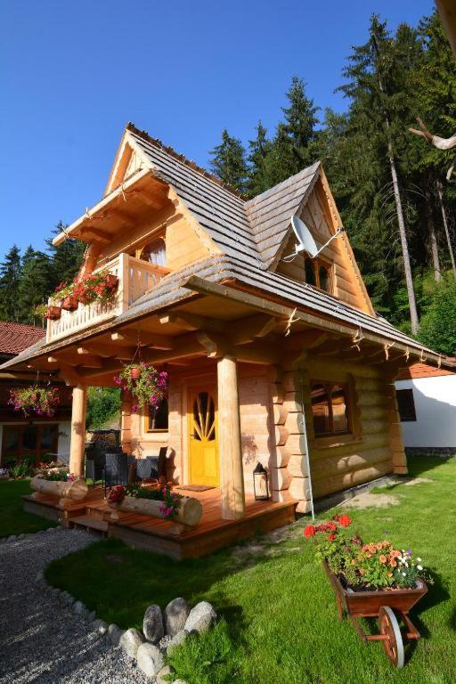 a small log cabin with a yellow door and flowers at Chalets Adriana in Belá