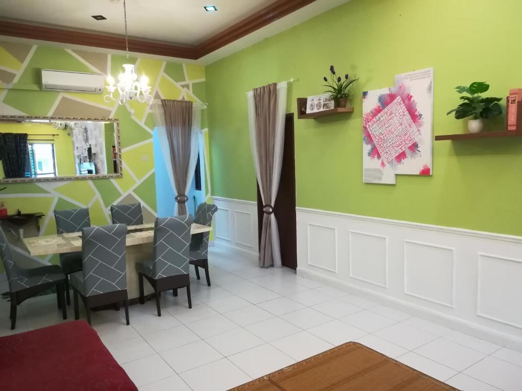 a dining room with green walls and a table and chairs at D Wangi Homestay Pasir Gudang at Ecotropic in Pasir Gudang