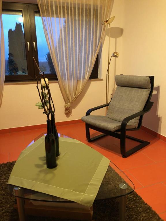 ein Wohnzimmer mit einem Stuhl und einer Vase auf einem Tisch in der Unterkunft Appartement Rosengarten in Wachtberg