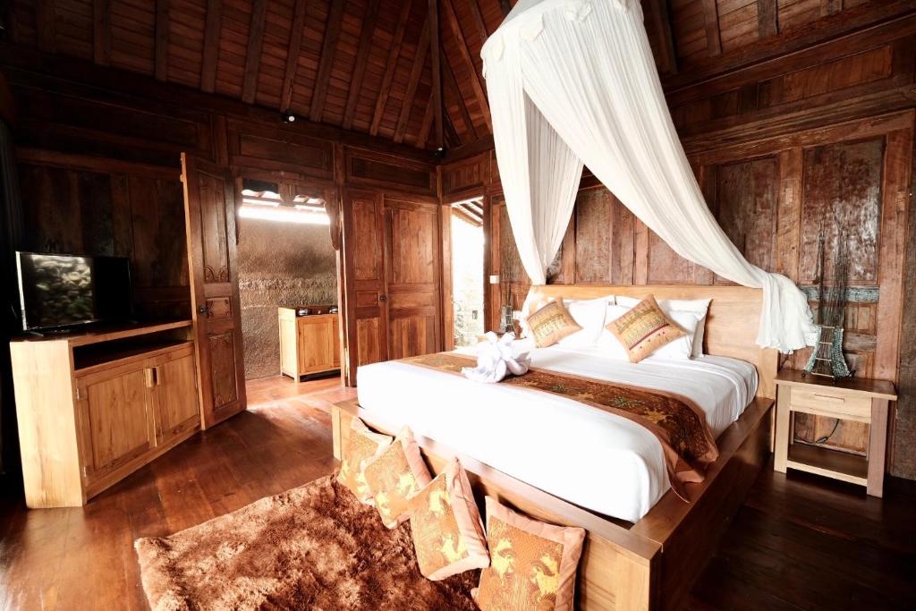 - une chambre avec un lit et une télévision dans l'établissement Bumbung Sari Villa, à Ubud