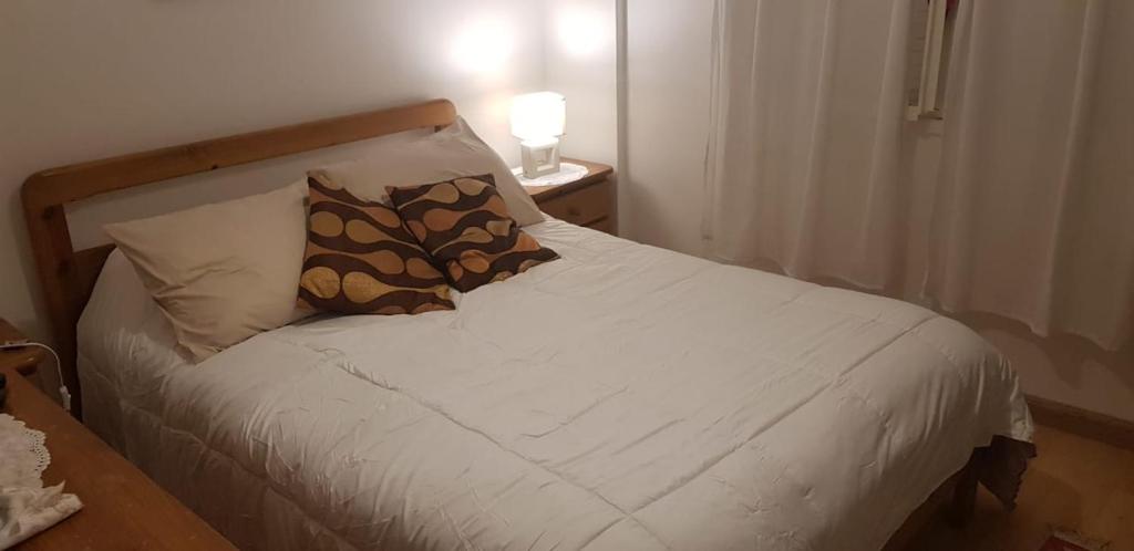 a white bed with a pillow and a lamp on a table at MDQ 4to20 in Mar del Plata