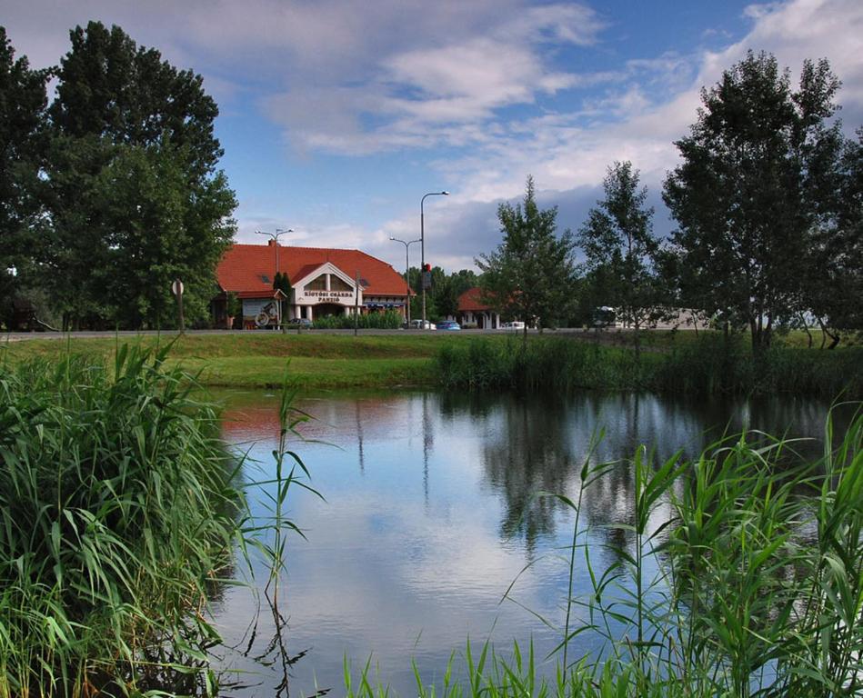 uma casa e um lago em frente a uma casa em Kígyósi Csárda & Panzió em Fülöpszállás