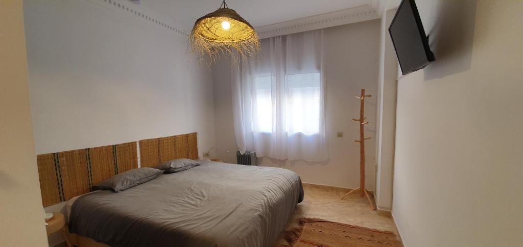 a bedroom with a bed and a window and a chandelier at FRESH DESIGNED next to THE SEA -nice area - wifi in Essaouira