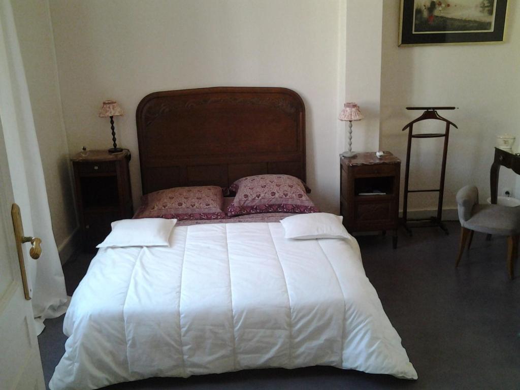 a bedroom with a large white bed with two night stands at L&#39;Ecrin in Villeneuve-sur-Lot