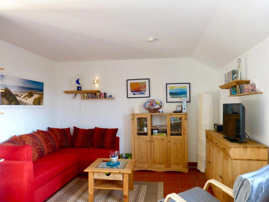 ein Wohnzimmer mit einem roten Sofa und einem TV in der Unterkunft Gemütliches Apartment in Strandnähe in Dranske