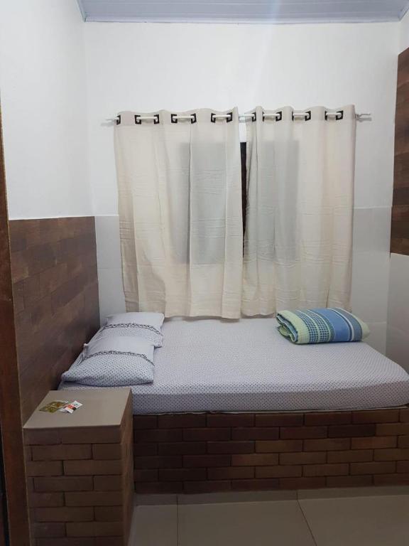 uma cama num quarto de tijolos com uma janela em Pouso Quarto sem suíte em Pirenópolis