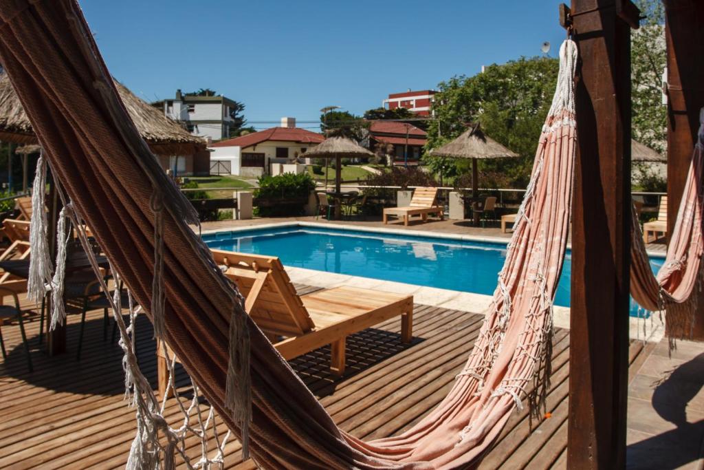 a hammock on a deck next to a swimming pool at Alpemar Apart Hotel & Spa in Villa Gesell