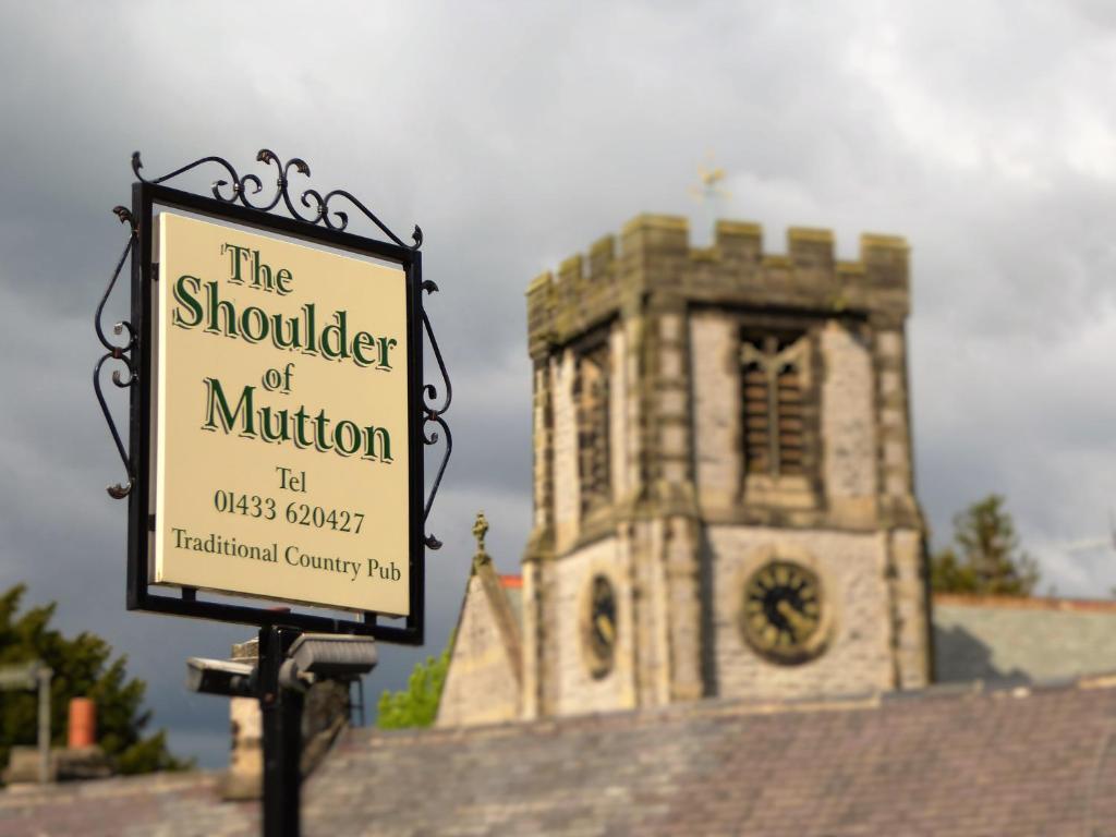 a sign in front of a building with a clock tower at The Shoulder of Mutton in Bradwell