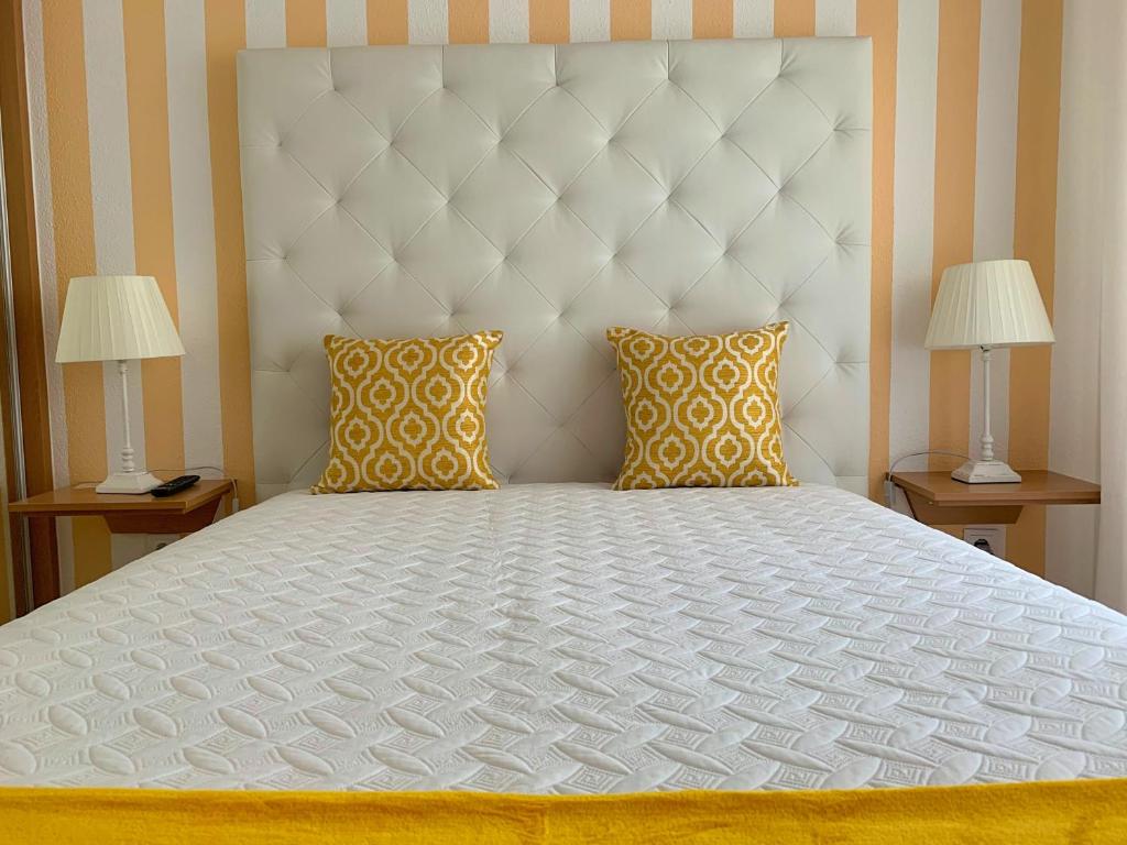 ein Schlafzimmer mit einem großen weißen Bett mit zwei Lampen in der Unterkunft Duarte Houses T2 - com vista mar in Nazaré