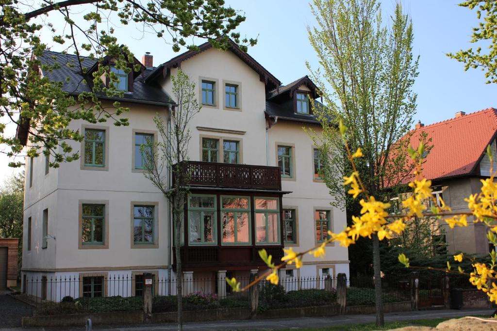 uma grande casa branca com uma varanda em Traumhafte Etagenwohnung in Günderzeitvilla em Dresden