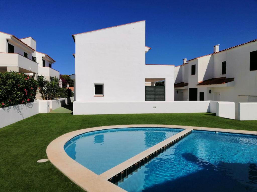 a villa with a swimming pool in front of a house at VILLA PIÑUELO (RELAX EN EL PARAÍSO). in Es Mercadal