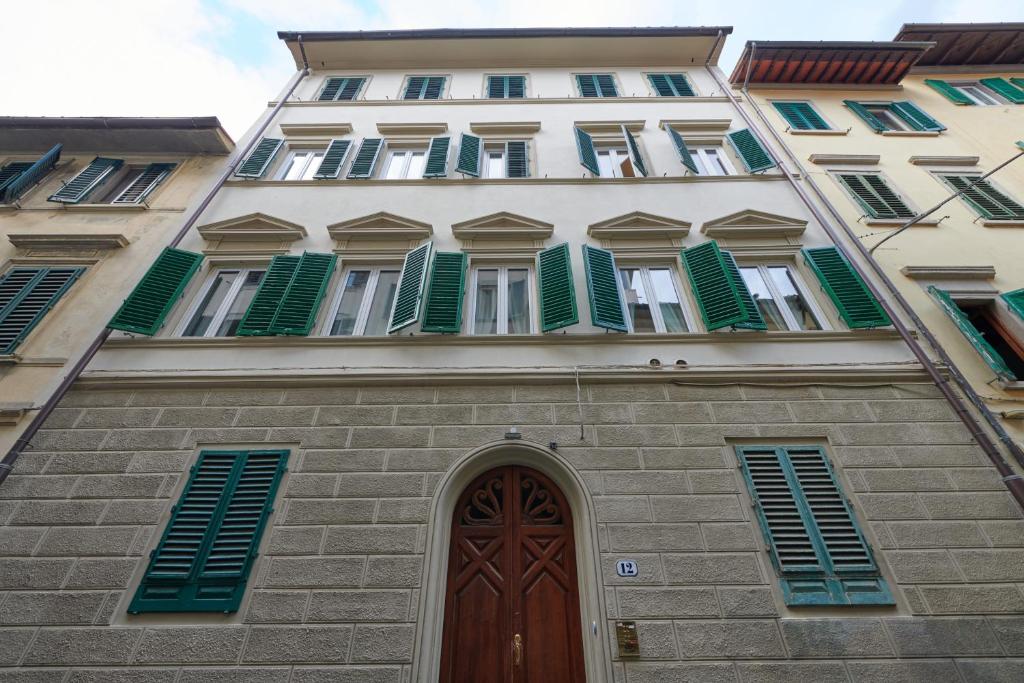 フィレンツェにあるFlorence&Us Santa Croceの緑のシャッター付き窓とドアのある高層ビル