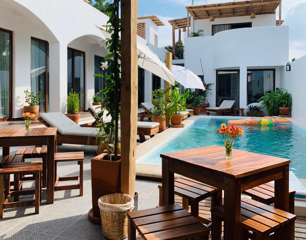 a patio with tables and chairs next to a swimming pool at Casa Beu in Puerto Escondido