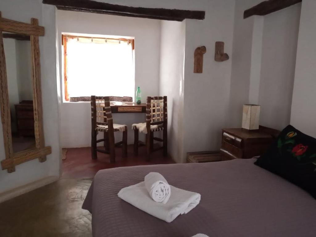a bedroom with a bed with a hat on it at Hosteria La Pushka in Purmamarca