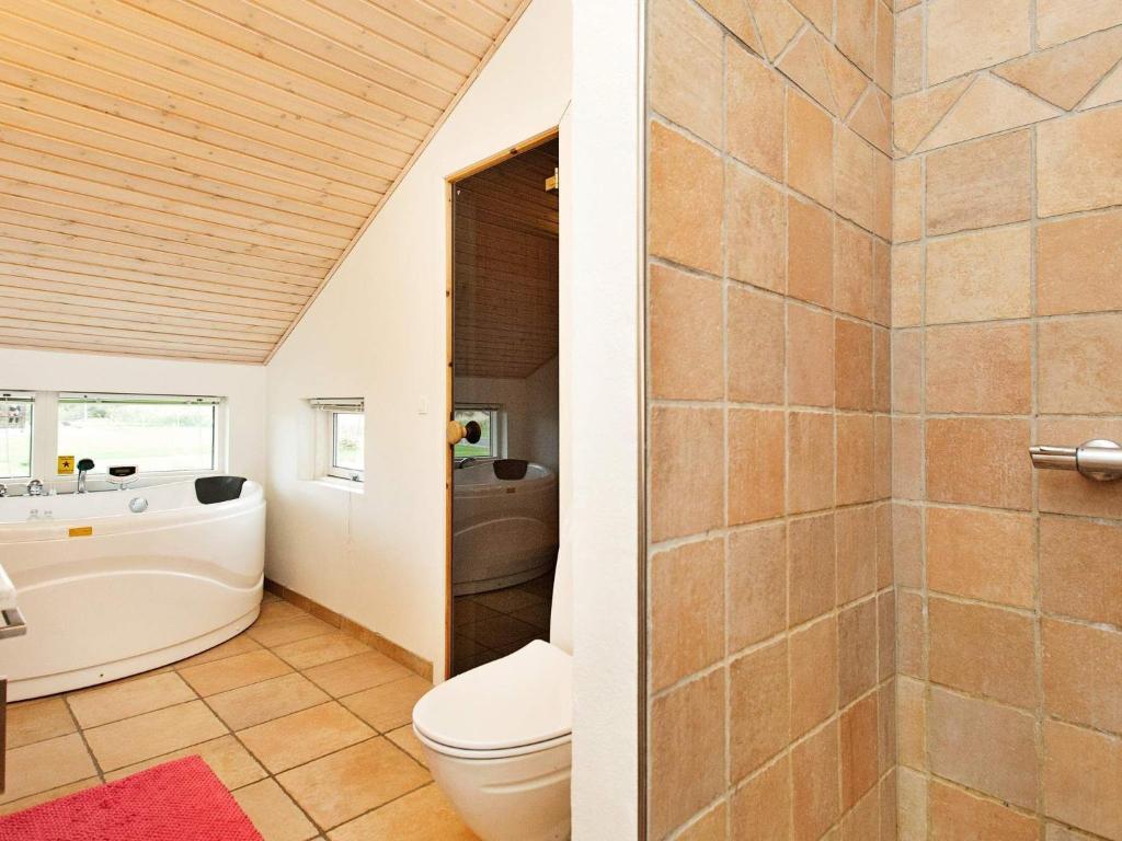 a bathroom with a tub and a toilet and a sink at 7 person holiday home in R dby in Rødby