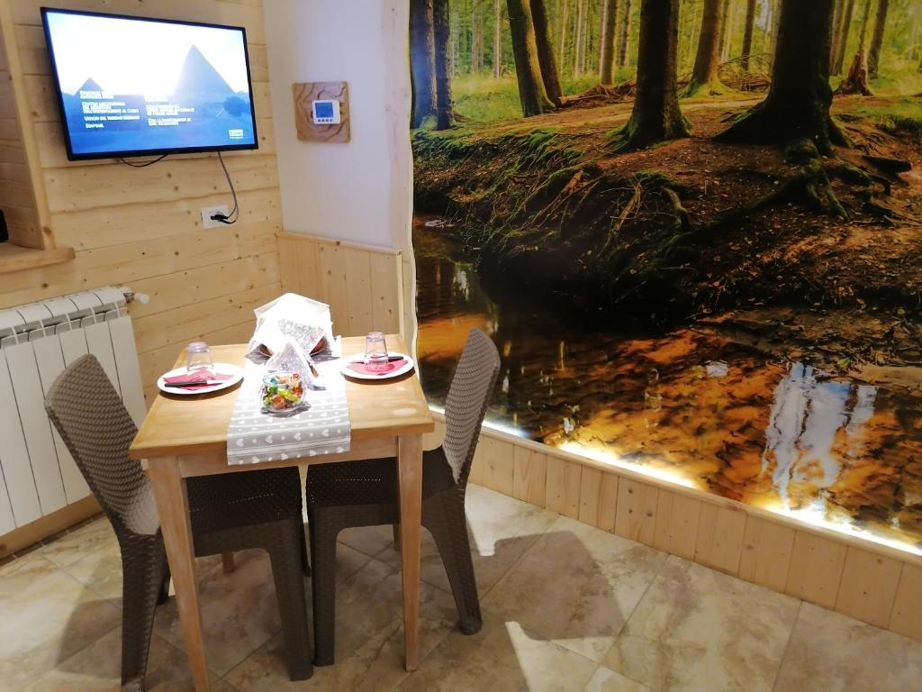 stół z dwoma krzesłami i telewizor w lesie w obiekcie Villa Sofia-La camera nella Riserva w mieście Pettorano sul Gizio