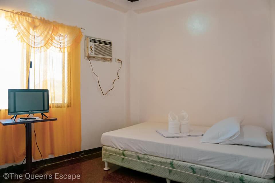 a bedroom with a bed with a television and a window at King Michael Coron in Coron
