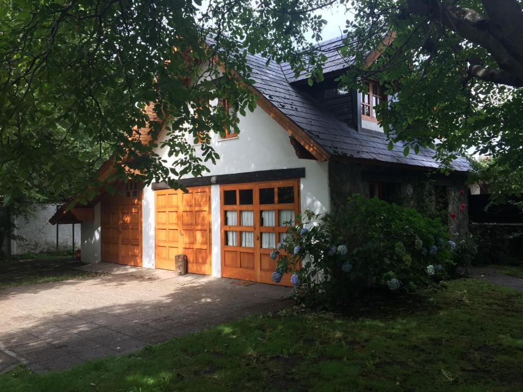 a white house with a wooden garage door at Casa de Huéspedes Silvana in San Martín de los Andes