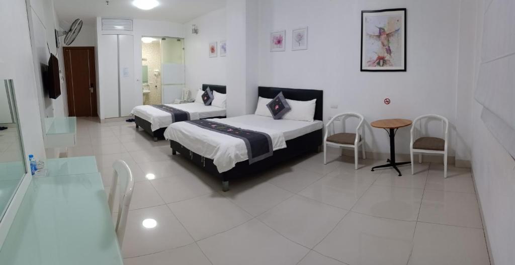 1 dormitorio con 2 camas, mesa y sillas en Linh Anh Hotel, en Hanói