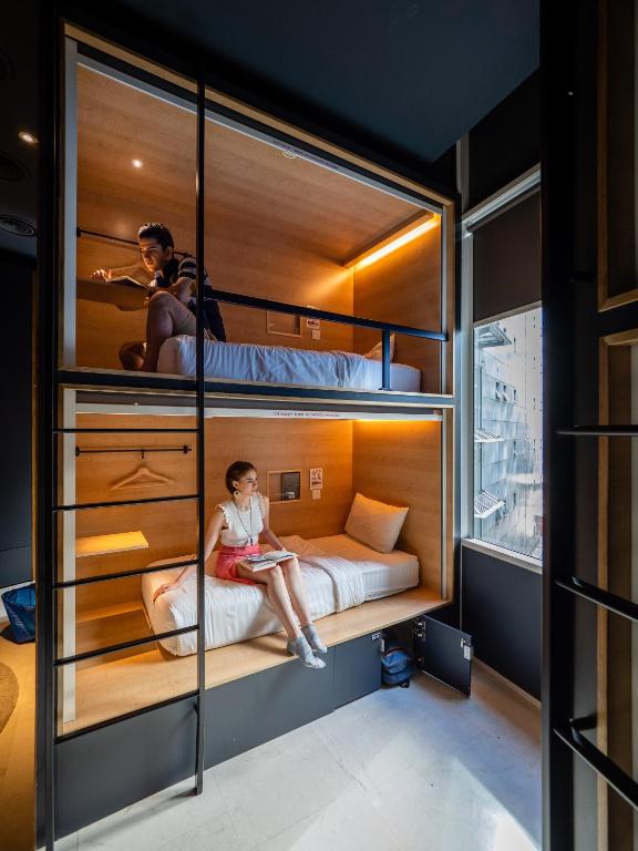 a woman sitting on a bed in a bunk room at The Bed KLCC in Kuala Lumpur