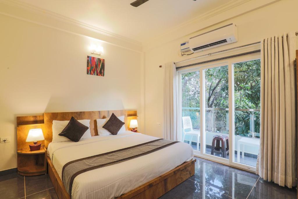 a bedroom with a bed and a large window at Aaria Residency in Arambol