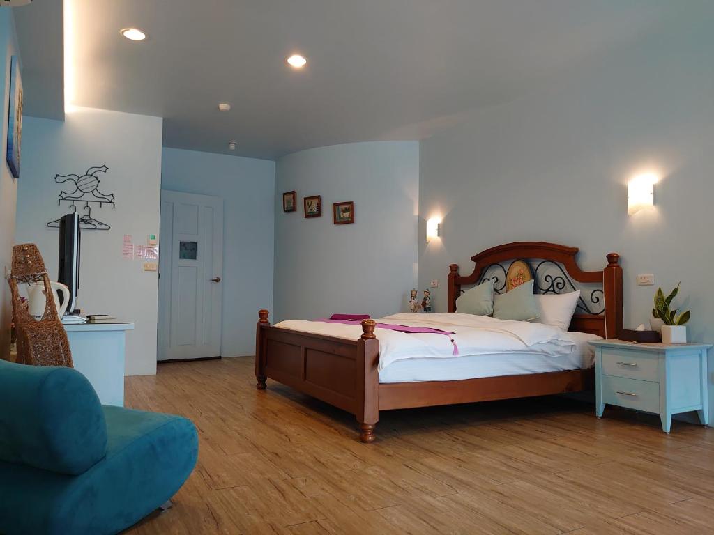 a bedroom with a large bed and a blue chair at Lotus Hostel Beicheng Zhuang in Luodong