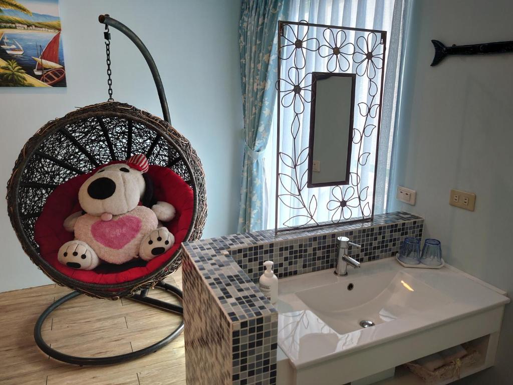 a bathroom with a teddy bear in a basket next to a sink at Lotus Hostel Beicheng Zhuang in Luodong