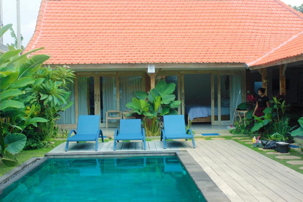 ein Haus mit einem Pool und zwei blauen Stühlen in der Unterkunft Peaceful Haven 6BR Private Pool Villa in Canggu in Canggu