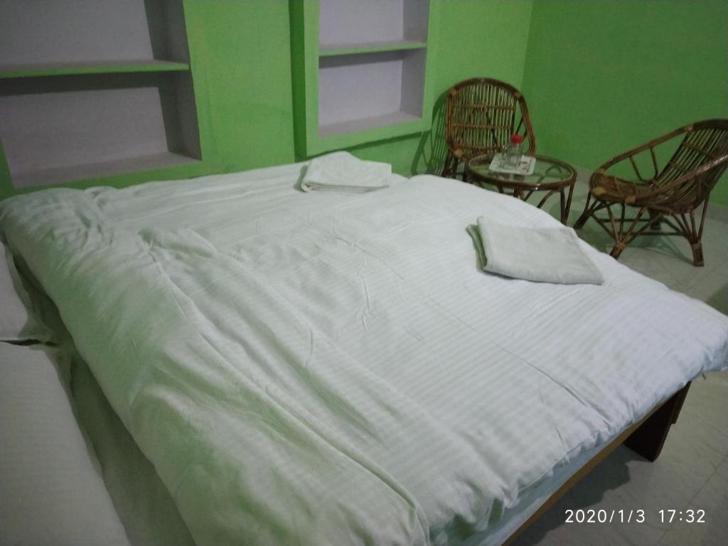 a large white bed in a room with two chairs at Homes of India in Orchha