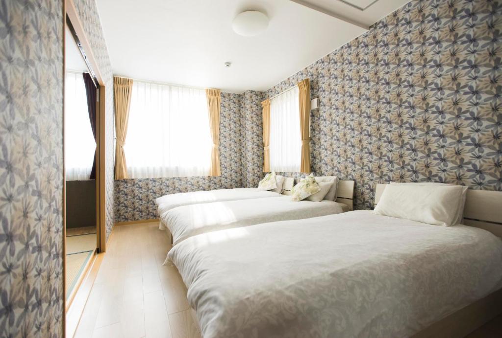 eine Reihe von Betten in einem Hotelzimmer in der Unterkunft guest house Sora in Osaka
