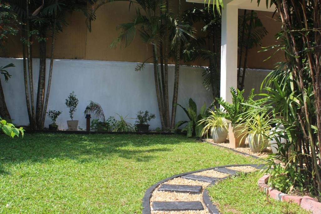 a garden with palm trees and a stone walkway at Natures Bliss Holidays in Ja-Ela
