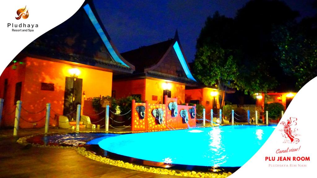 a swimming pool in front of a building at night at Pludhaya Resort & Spa in Phra Nakhon Si Ayutthaya