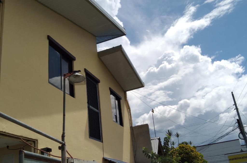 a building with a window and a cloudy sky at Eurich Ladies Dormitory in Butuan