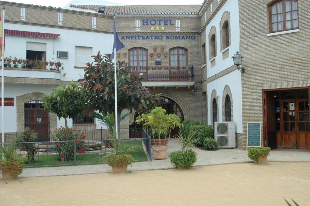 un hotel con bandera frente a un edificio en Hotel Anfiteatro Romano en Santiponce