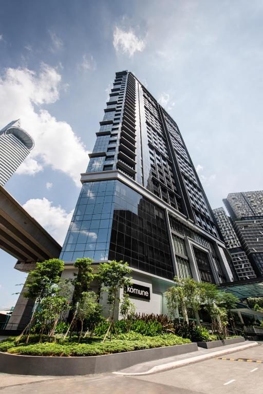 a tall glass building with trees in front of it at Komune Living in Kuala Lumpur