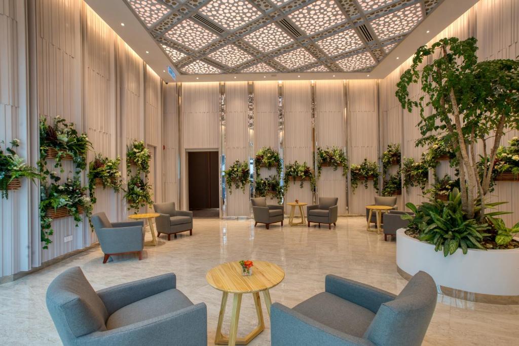 a lobby with chairs and tables and plants at Komune Living in Kuala Lumpur