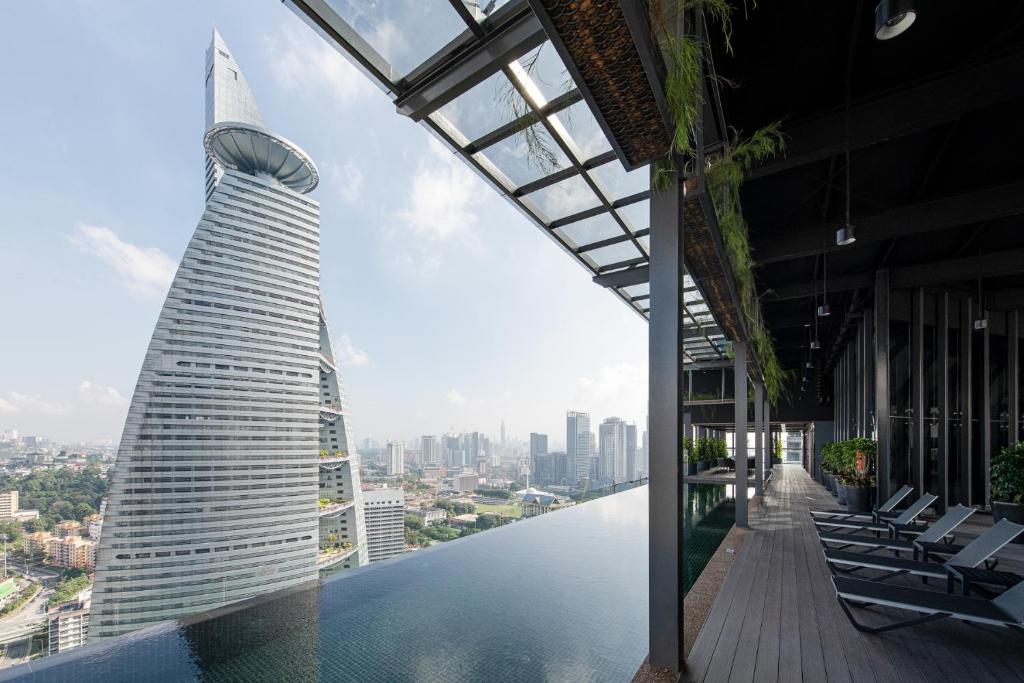 a building with a swimming pool next to a city at Komune Living in Kuala Lumpur