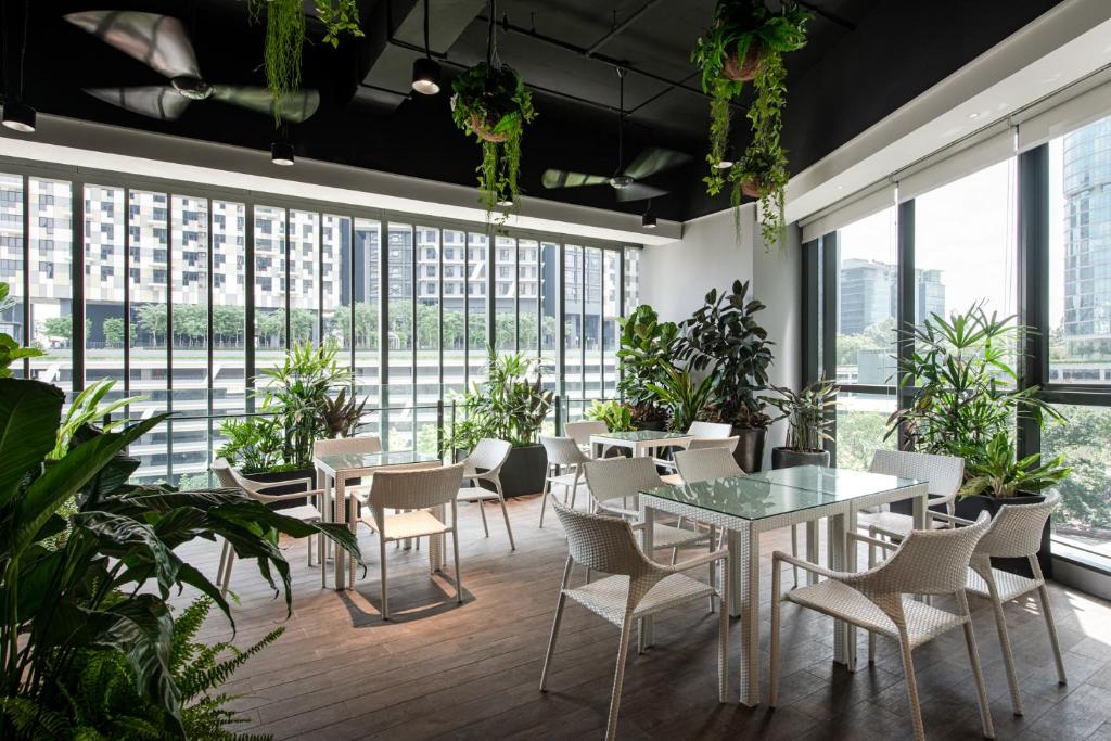 a restaurant with tables and chairs and plants at Komune Living in Kuala Lumpur